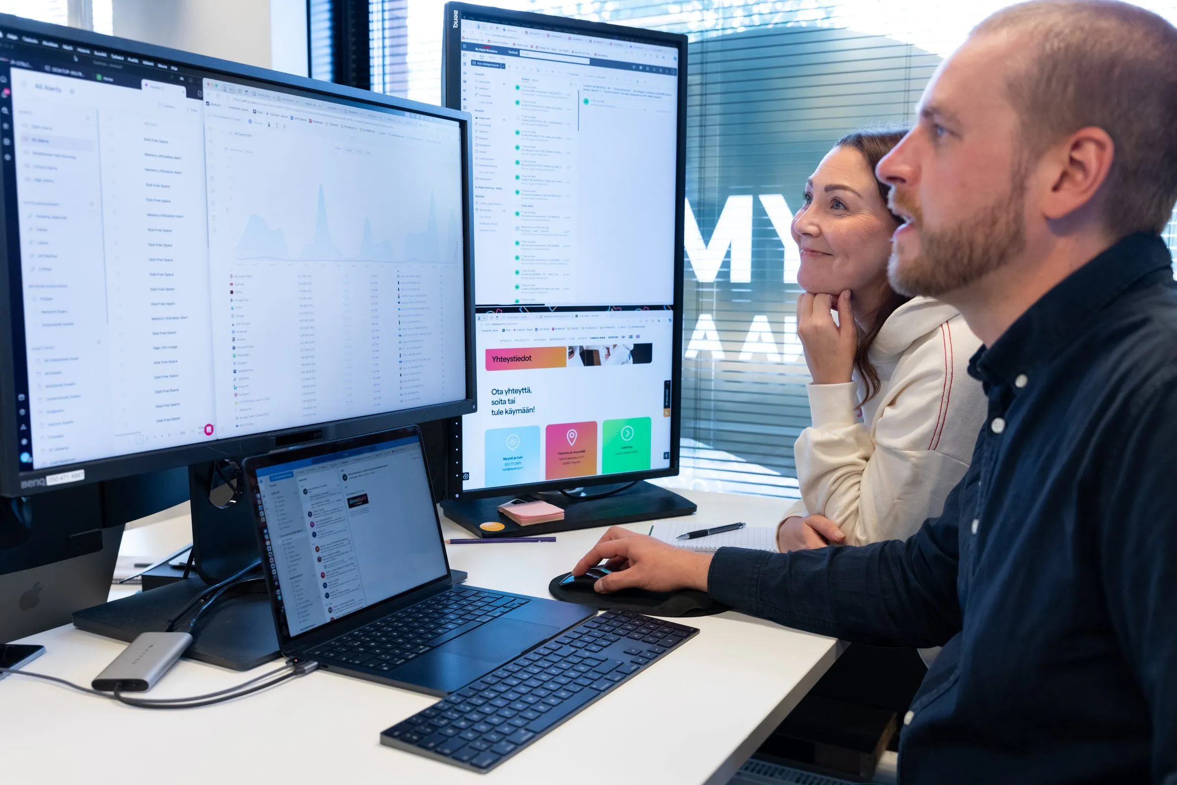 Kaksi Developitin työntekijää katsoo yhdessä näytöiltä järjestelmän valvontanäkymää ja raportteja.
