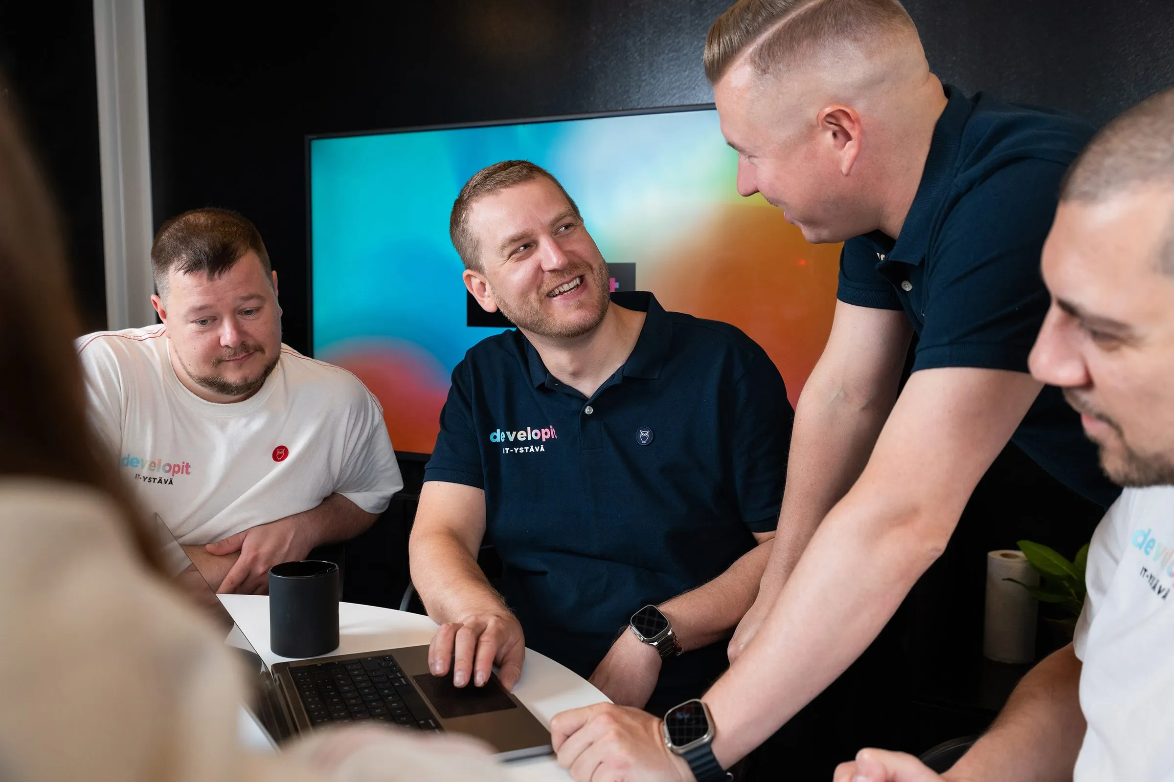 Developitin tiimi kokoontuneena kannettavan ympärille.