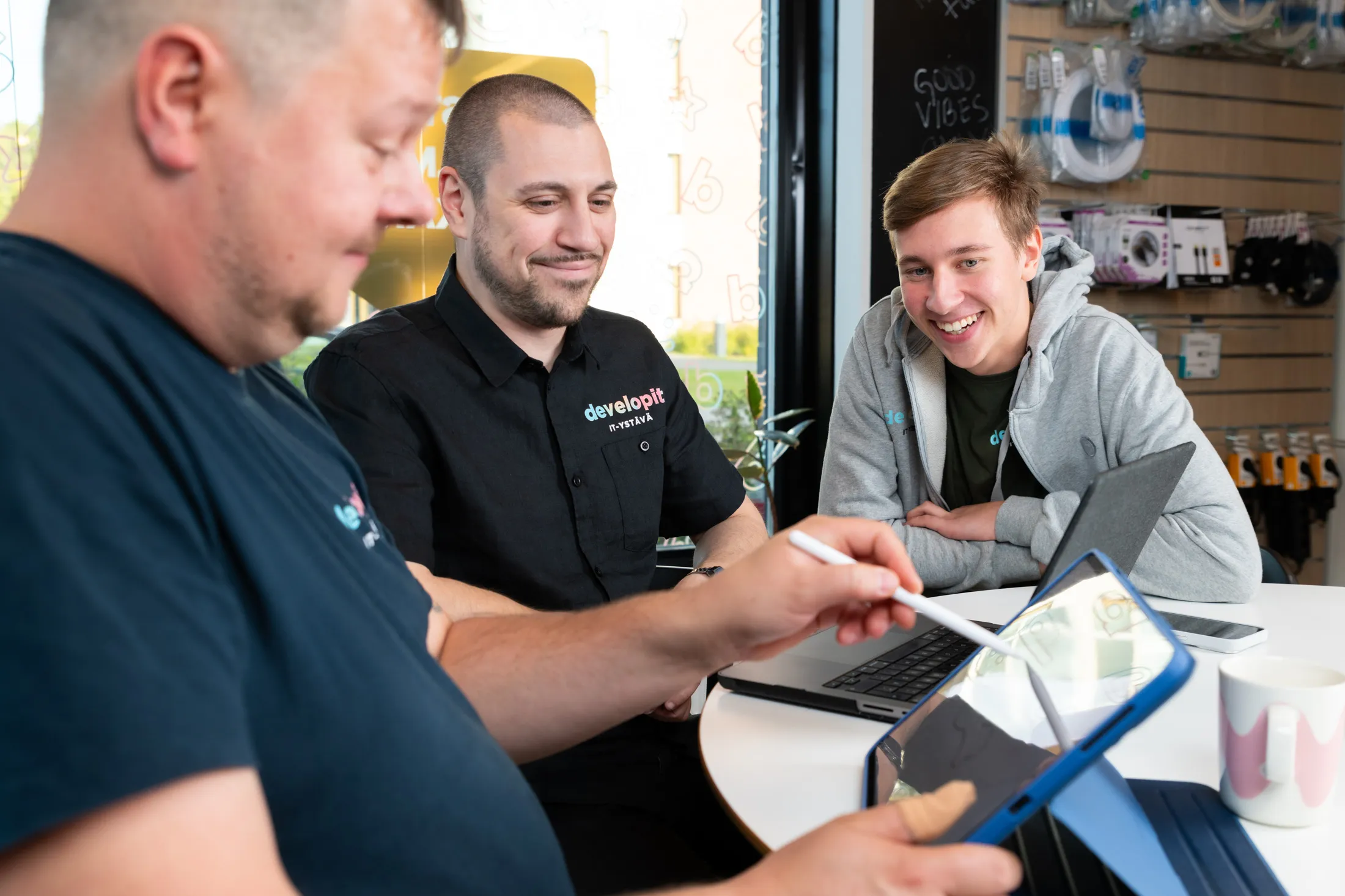 Kolme Developitin työntekijää keskustelee kannettavien ja tabletin äärellä.